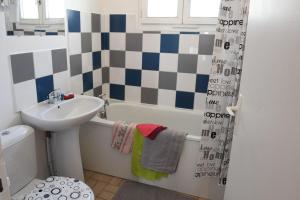 a bathroom with a sink and a bath tub with a shower curtain at La Belle Onde in Dieppe