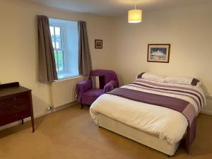 a bedroom with a bed and a purple chair at Pass the Keys Charming 3br Listed Cottage in Historic Wigtown in Newton Stewart