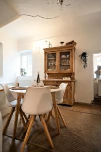 a dining room with a table and white chairs at Schlaf.Cabinet im Bio.Weingut (Lesehof seit 1424) in Krems an der Donau