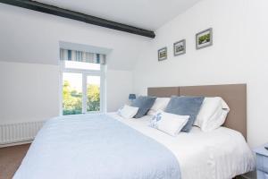a bedroom with a large white bed with a window at Drovers Cottage in Tavistock