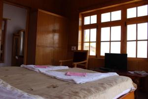 a bedroom with a large bed with a desk and windows at Hotel Skittsal Leh in Leh