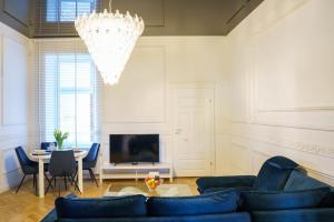 a living room with a blue couch and a chandelier at Prestige Apartment Rynek Kielce in Kielce