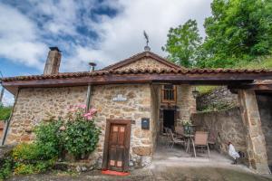 una pequeña casa de piedra con mesa y sillas en Casa Rural La Carrozal Senda del Oso en Orelleiru