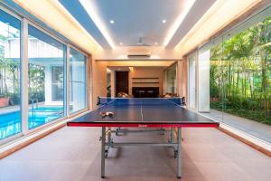 a ping pong table in a room with windows at StayVista's Bianco Villa - Hill-View Villa with Private Pool, Jacuzzi, Gym & Games Room in Lonavala