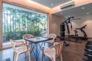 a fitness room with a table and chairs and a gym at StayVista's Bianco Villa - Hill-View Villa with Private Pool, Jacuzzi, Gym & Games Room in Lonavala +38 photos