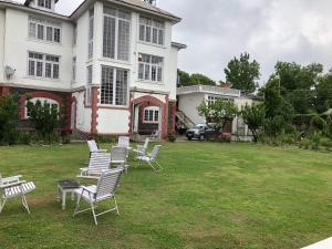 Un grupo de sillas colocadas en un césped frente a una casa. en Hotel Ashai, en Srinagar