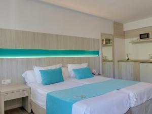 a bedroom with a large white bed with blue pillows at Comitas Floramar in Cala Galdana
