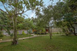 a garden with trees and a building in the background at Atha Resort in Sigiriya