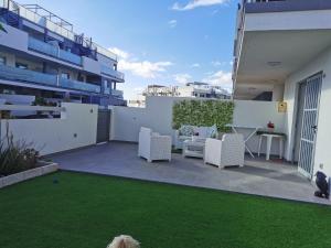 a patio with white furniture and a green lawn at Divino en playa in Granadilla de Abona