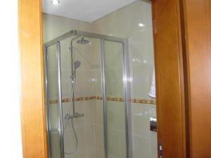 a shower with a glass door in a bathroom at Muralha House in Lagos
