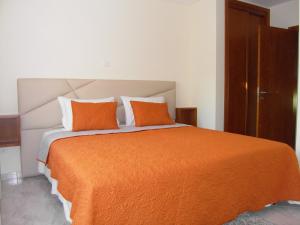 ein Schlafzimmer mit einem großen Bett mit einer orangefarbenen Decke in der Unterkunft Muralha House in Lagos