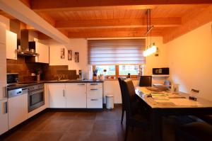 uma cozinha com armários brancos e uma mesa com cadeiras em Feriendorf Via Claudia Haus 100 Dominique em Lechbruck