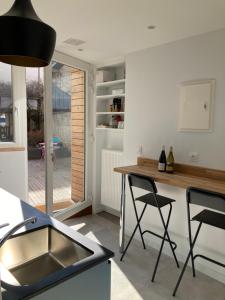 eine Küche mit einer Spüle und einer Theke mit Stühlen in der Unterkunft Appart' Au Coeur de Nuits in Nuits-Saint-Georges
