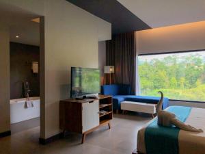 a hotel room with a television and a dinosaur on a bed at Hotel Dafam Wonosobo in Wonosobo