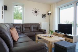 sala de estar con sofá marrón y TV en Duenenpark-Heiligenhafen-Haus-Meerduene-Wohnung-2-Meertraum, en Heiligenhafen