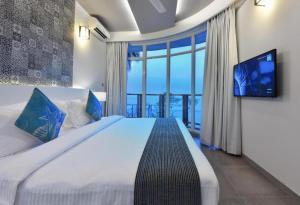 um quarto com uma cama grande e uma televisão de ecrã plano em Velana Beach Hotel Maldives em Maafushi