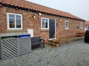 a brick house with a porch and a bench at Cosy Cottage,The Paddock BARMSTON. NR BRIDLINGTON in Great Driffield