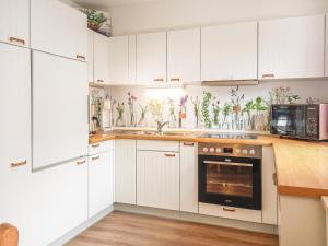a kitchen with white cabinets and flowers on the wall at Ferienhaus Frühlingstraße in Sonthofen