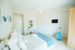 a white bedroom with a bed and a television at Frida Apartments in Benitses