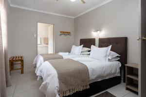 a bedroom with two beds with white sheets and pillows at Rosepark Guesthouse in Bloemfontein