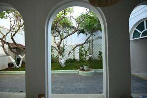um arco que leva a um pátio com uma árvore em La Cedille - French Heritage House em Pondicherry