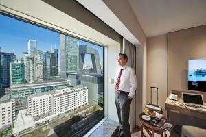 um homem de pé numa sala com uma grande janela em China World Hotel, Beijing em Pequim