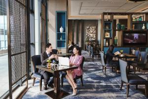 un hombre y una mujer sentados en una mesa en un restaurante en China World Hotel, Beijing en Pekín
