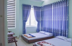 1 dormitorio con 2 camas y una ventana con cortinas azules en MINH THU MOTEL, en An Bình (1)