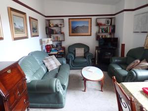 キンクレイグにあるJura Cottageのリビングルーム(緑のソファ2台、テーブル付)