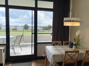 ein Esszimmer mit einem Tisch und einem großen Fenster in der Unterkunft Fehmarn Burgtiefe Südstrand Whg SEESTERN in Fehmarn