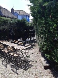 une table de pique-nique et des bancs à côté d'une brousse dans l'établissement Maison en bord de mer, à Blonville-sur-Mer