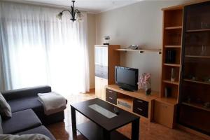 sala de estar con sofá y TV en Desconectaengalicia La Perla, piscina y parking, en Sanxenxo