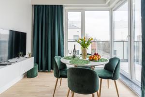jadalnia ze stołem i zielonymi krzesłami w obiekcie Langgarten Apartments by Little Heaven w Gdańsku