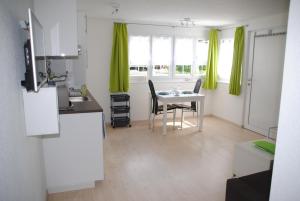 cocina y comedor con mesa y cortinas verdes en Ferienwohnung Grütter en Seedorf