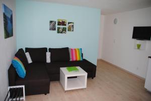 sala de estar con sofá negro y mesa en Ferienwohnung Grütter en Seedorf