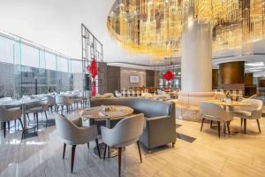 a restaurant with tables and chairs and a chandelier at Ramada Plaza Pudong Shanghai in Shanghai