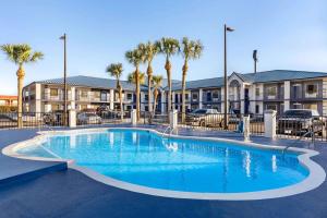 a swimming pool in front of a building with palm trees at Days Inn by Wyndham Kingsland GA in Kingsland