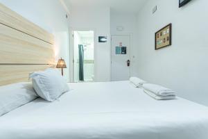 a white bed sitting in a bedroom next to a window at Easy Sants by Bossh! in Barcelona