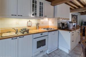 a kitchen with white cabinets and a stove top oven at La Maisonnette in Chaudenay-le-Château +6 photos