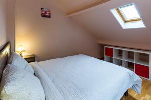 um quarto com uma cama branca e uma clarabóia em La Maisonnette em Chaudenay-le-Château
