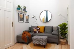 ein Wohnzimmer mit einem grauen Sofa und einem Spiegel in der Unterkunft BpR Pastellion Art Home in Buda in Budapest