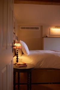 1 dormitorio con 1 cama y 1 mesa con lámpara en The Bell & Crown, en Zeals