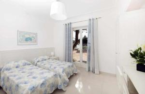 アナカプリにあるBeB Casa Romanoの白い部屋で、ベッド2台、窓が備わります。