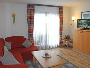 Sala de estar con sofá rojo y mesa de centro en Ferienhaus Nr 48, Kategorie Komfort, Feriendorf Hochbergle, Allgäu, en Bichel