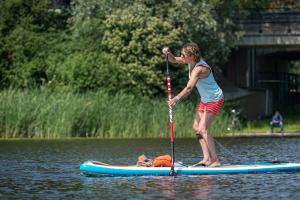 une femme debout sur une planche de paddle sur l'eau dans l'établissement Buiten aan de Baak, à Steenbergen