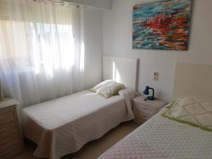 a bedroom with two beds and a painting on the wall at El Pilar Solo Familia Serviplaya!!! in Playa de Xeraco