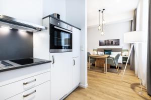 une cuisine avec des armoires blanches et une table dans une pièce dans l'établissement Ferienapartments am Krusespeicher Ferienapartments am Krusespeicher 0-01, à Wismar