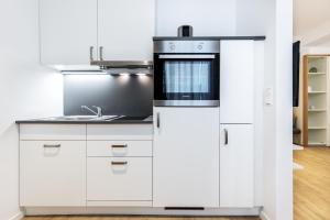 une cuisine avec des armoires blanches et un évier dans l'établissement Ferienapartments am Krusespeicher Ferienapartments am Krusespeicher 0-01, à Wismar 8 autres photos