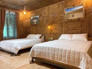 two beds in a room with wooden walls at Trang An Homestay in Ninh Binh +11 photos