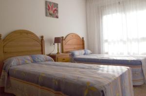 een slaapkamer met 2 bedden en een raam bij Desconectaengalicia La Perla, piscina y parking in Sanxenxo